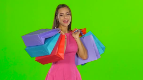 Woman smiling while holding shopping bags. Green screen — Stockvideo