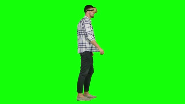 Человек играет в виртуальную игру дополненной реальности с установленным на голове дисплеем. Зеленый экран — стоковое видео
