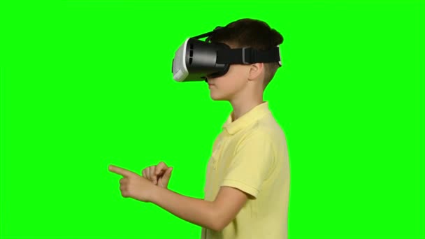 Хлопчик використовує шолом гарнітури віртуальної реальності. Зелений екран — стокове відео