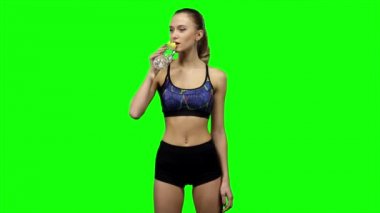 Woman in sportswear drinking water from bottle. Green screen