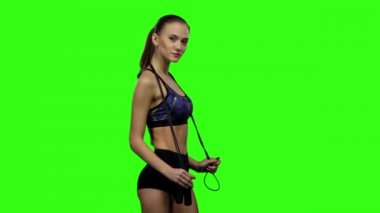 Woman holding jump rope on her shoulders. Slow motion. Green screen
