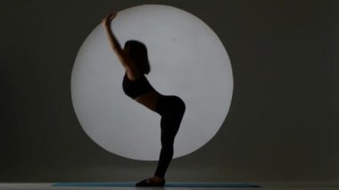 Jimnastikçi ileriye ve geriye doğru tilt gerçekleştirir. Arka ışık. Siluet