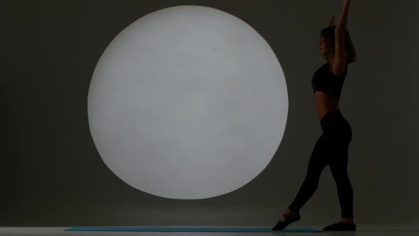 Chica haciendo volteretas en un gimnasio. Luz trasera. Silueta — Vídeos de Stock