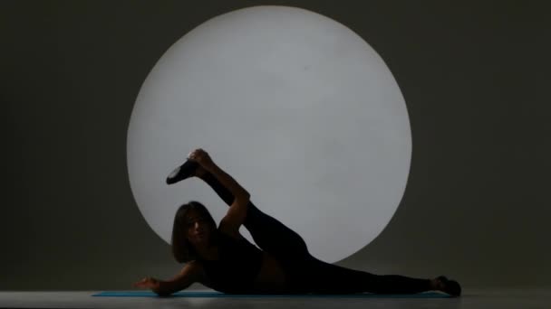 Žena, která dělá protahovací cvičení. Zadní světlo. Silueta — Stock video