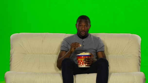 Mann schaut Film auf Couch und isst Popcorn. Green Screen — Stockvideo