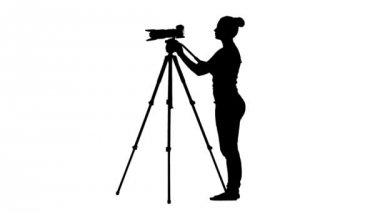 Operatör silüeti kamera tripod üzerinde çalışır. Beyaz arka plan