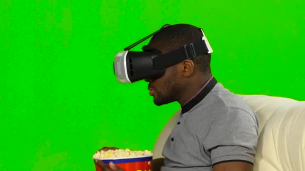Hombre con una máscara VR viendo una película y comiendo palomitas de maíz. Pantalla verde — Vídeos de Stock