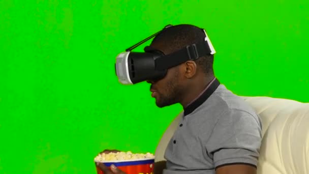 Man in het masker van een Vr een film kijken en eten popcorn. Groen scherm — Stockvideo