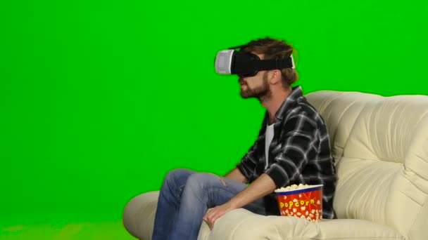 Muž v masce VR sledoval film a jedl popcorn. Zelená obrazovka — Stock video