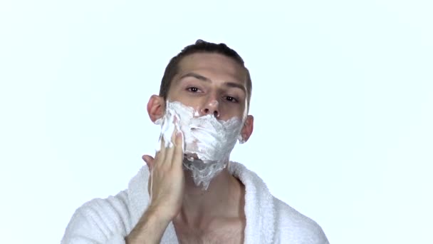 Ο άνθρωπος παίρνει το ξύρισμα βοήθεια στο πρόσωπο. Λευκό φόντο. Αργή κίνηση — Αρχείο Βίντεο