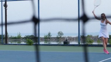 Woman hitting tennis ball with racquet