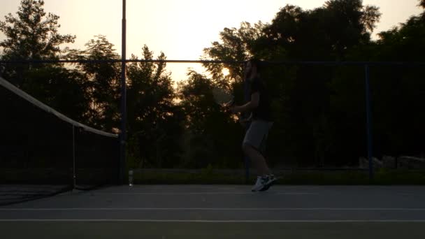 Muži hrají tenis při západu slunce