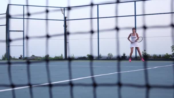 Girl tennis player expecting the tennis ball on court, net in front. Dolly shot — Stock Video