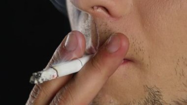 Karanlık bir odada bir sigara içiyor. Siyah. Yakın çekim