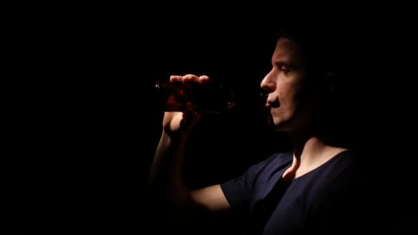 Dépendance à l'alcool. Alcoolisme. Une bouteille de bière. Noir. Rétro-éclairage. Gros plan — Video