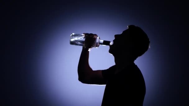 Ο άνθρωπος πίνει βότκα με λαιμό. Πίσω φως — Αρχείο Βίντεο
