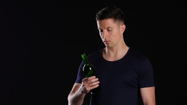 Εθισμός στο αλκοόλ. Ο άνθρωπος που πίνει νερό από ένα μπουκάλι κόκκινο κρασί. Μαύρο — Αρχείο Βίντεο