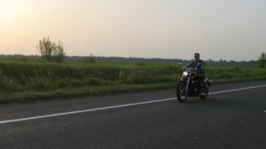 Adam bir motosiklet sürmek, gün batımı. Genel gider atış
