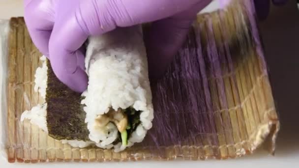 Sushi-master gira un lungo rotolo di tappetino di bambù. Da vicino. — Video Stock