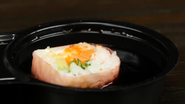 Person lowers his sushi in soy sauce by chopsticks. Close up — Stock Video