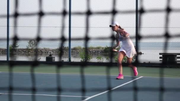 Auf dem Tennisplatz - Personal Trainer, der einen Tennisspieler trainiert. Netz vorne. Dollly. Zeitlupe — Stockvideo