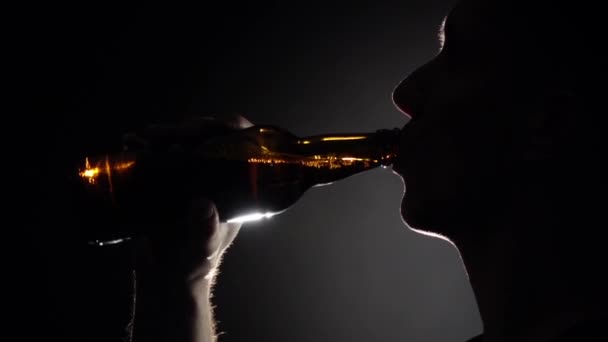 L'uomo beve birra da una bottiglia. Grigio. Silhuoette. Chiudete. Rallentatore — Video Stock