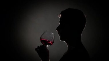 Adam bardaktan konyak içer. Gri. Siluet. Yakından kapatın. Yavaş çekim