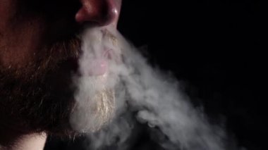 Adam sigara içiyor ve burun deliklerinde duman soluyor. Siyah. Siluet. Yavaş çekim