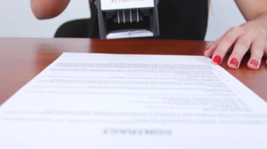 Woman puts a stamp on a contract thereby approving of this condition. Close up