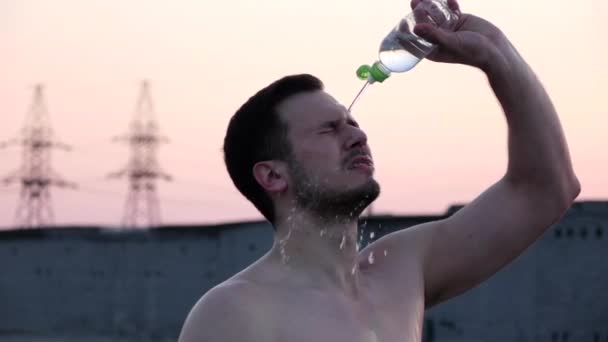 Fitness homme boire de l'eau de bouteille éclaboussant l'eau dans le refroidissement du visage après l'entraînement en cours sur la plage. Athlète assoiffé ayant froid boisson rafraîchissante transpiration après un exercice intense. MOTION DE LENT . — Video