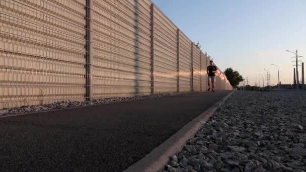 Man loopt op bergweg bij zonsondergang. Slow Motion. Dolly schot — Stockvideo