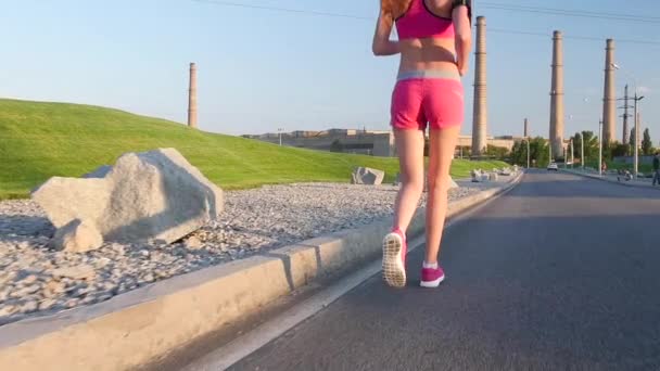 Imágenes deportivas, detalle piernas de mujer corriendo por la calle vacía al lado de campos de maíz, filmadas en prores. Movimiento lento — Vídeo de stock