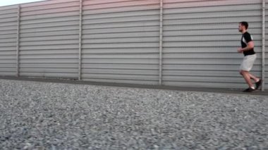 Atletik fit genç spor fitness modeli doğada dışında yolda tam vücut uzunluğu onun yirmili. Yavaş çekim