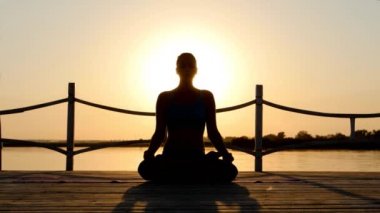 Genç kadın güneş doğarken pratik Yoga