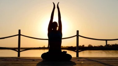 Gün batımında sahilde sunflares Yoga pratik genç kadın