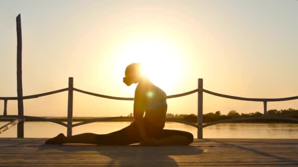 Femme mince faisant du yoga sur le soleil orange — Video