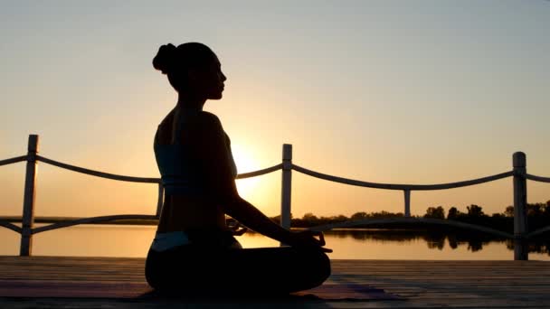 Frau meditiert in Pose Lotus über oranger Sonne — Stockvideo