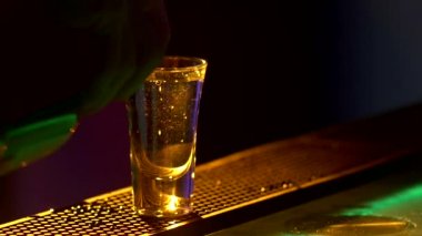 Barmen kokteyl yapıyor ve üç farklı sıvı ekleyerek, bar sayacı kenarında, çekim, arka ışık, yavaş hareket