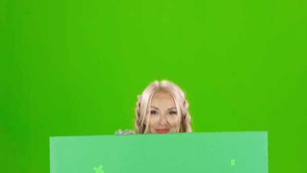 Bavarian girl looks out from behind a with a glass of beer and winking . Green screen — Stock Video