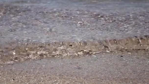 Blick aus der Vogelperspektive auf schäumende Meereswellen, die auf einen Kiesstrand krachen. Zeitlupe. Nahaufnahme — Stockvideo