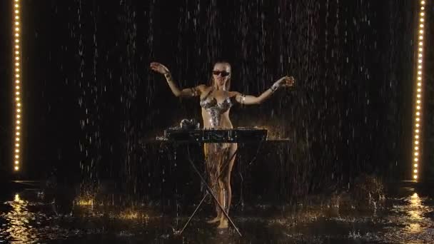 Hermosa hembra dj tocando música en la fiesta. Sexy rubia está bailando mientras disfruta de la música bajo la lluvia. Cuerpo desnudo mojado en gotas de agua. Movimiento lento. — Vídeos de Stock