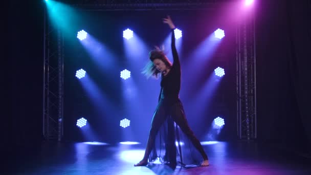 Импульсивный исполнитель танцует в современном стиле созерцания хореографии на черном фоне с голубыми огнями. Медленное движение. — стоковое видео