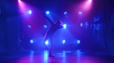Siyah elbiseli bir kadın dansçı mavi ışıkta modern koreografinin dokunaklı dans öğelerini sergiliyor. Siluet. Yavaş çekim.