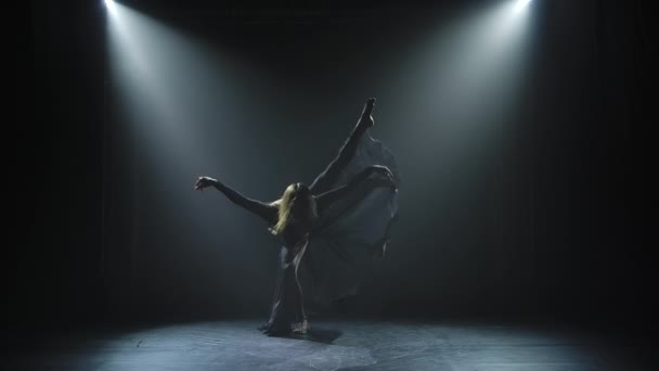 Молодая и энергичная женщина танцует презрение. Силуэт стройного танцора, который изящно движется в темной студии в центре внимания. Медленное движение. — стоковое видео