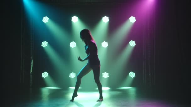 Giovane donna sexy danza disprezzo in lingerie nera. Coreografia romantica moderna su sfondo nero con riflettori in uno studio fumoso. Silhouette. Rallentatore. — Video Stock