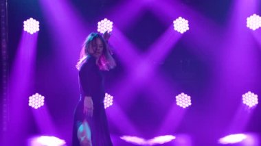 Genç bayan dansçı, mor ışıkların arka planında dans ederken şehvetli hareketler sergiliyor. Duygusal koreografi yapan zarif bir dansçıya yaklaş. Yavaş çekim