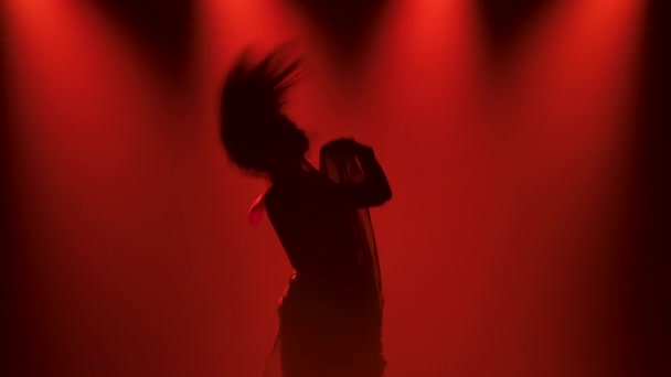 Moderní kontemplární tanec a štíhlá pružná tanečnice při taneční zkoušce v tmavém ateliéru s červenými světly. Silueta. Zavřít. Zpomalený pohyb. — Stock video