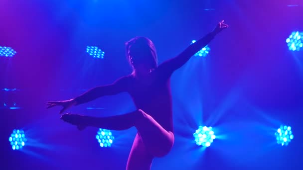 Härlig kvinna dansar ömt sensuellt förakt i en mörk studio mot bakgrund av blått ljus. Kvinnlig dansare ljuddämpare på nära håll. Långsamma rörelser. — Stockvideo