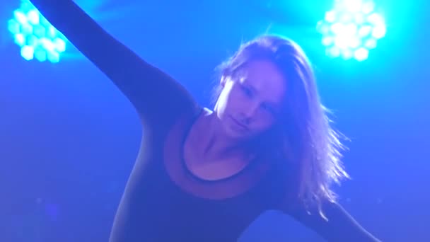 Een sierlijke jonge vrouw in een zwart lichaam en rok danst minachtend in de studioduisternis. Langzame beweging. Sluiten.. — Stockvideo