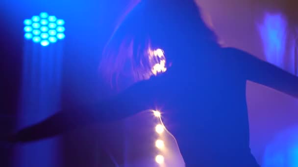 Jolie danseuse mince en costume noir exécutant une chorégraphie contemp en studio fumé avec lumière bleue. Silhouette d'un corps flexible en gros plan. Mouvement lent. — Video